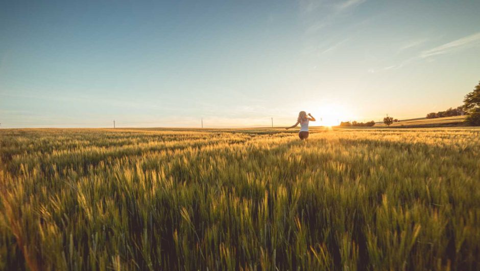 Young Woman Running Through Wheat Field on Sunset